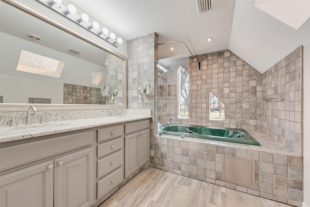 bathroom with lofted ceiling with skylight, a sink, double vanity, and wood finished floors