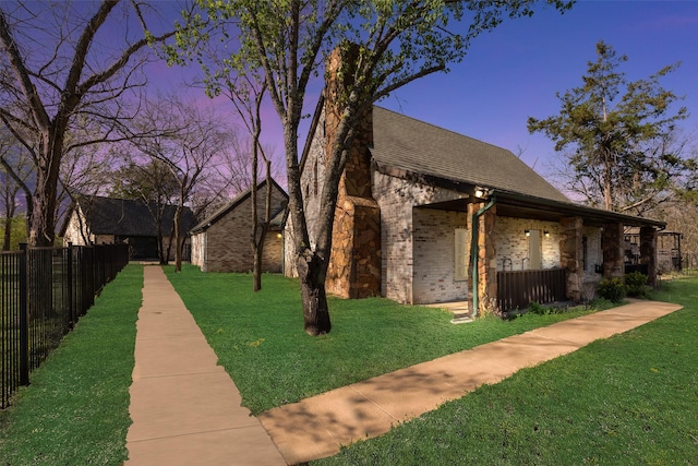 view of home's exterior with brick siding, fence, roof with shingles, and a yard