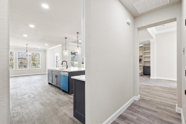 hallway featuring wood finished floors, a sink, baseboards, and visible vents