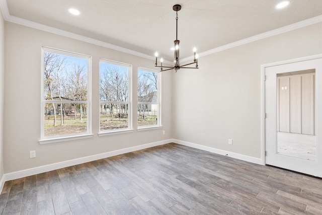 unfurnished dining area with crown molding, baseboards, an inviting chandelier, and wood finished floors