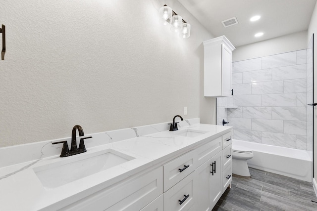 full bath featuring a sink, toilet, double vanity, and wood finished floors