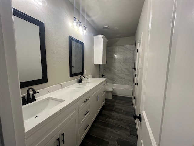bathroom featuring wood finished floors, double vanity, a sink, and visible vents