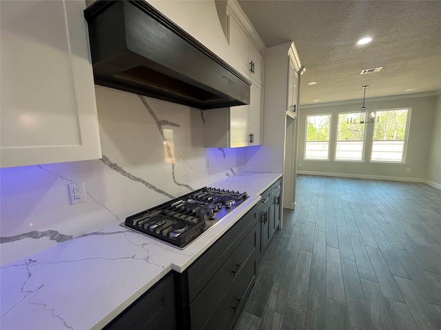 kitchen with white cabinets, exhaust hood, dark wood-style floors, a textured ceiling, and stainless steel gas cooktop