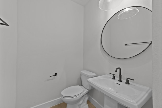 1330 Caleb Rd, Van Alstyne, TX 75495 - half bathroom featuring toilet, a sink, baseboards, and wood finished floors