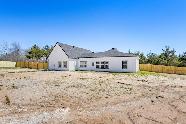 back of house featuring a fenced backyard and roof with shingles