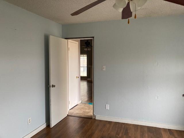 4220 Staghorn Cir N, Fort Worth, TX 76137 - empty room featuring a ceiling fan, dark wood finished floors, baseboards, and a textured ceiling