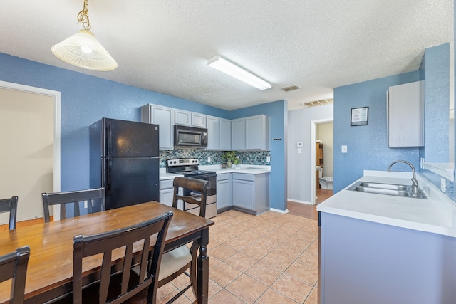 kitchen with black appliances, a sink, light countertops, light tile patterned floors, and a textured ceiling