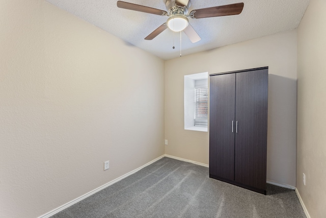 unfurnished bedroom featuring dark carpet, a textured ceiling, a ceiling fan, and baseboards