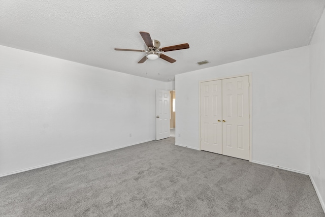 unfurnished bedroom featuring carpet flooring, a closet, baseboards, a ceiling fan, and a textured ceiling