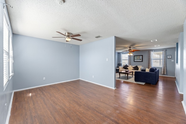 living area with ceiling fan, a textured ceiling, dark wood-style floors, and baseboards