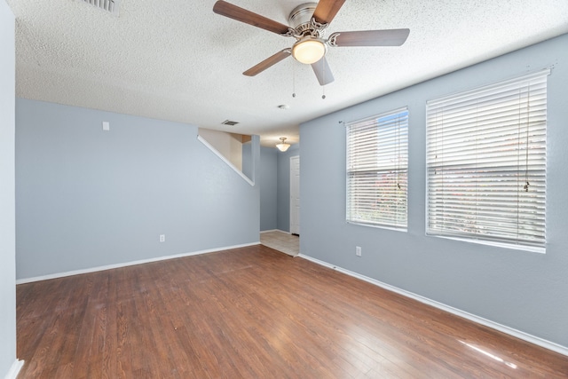 spare room featuring wood finished floors, ceiling fan, baseboards, and a textured ceiling