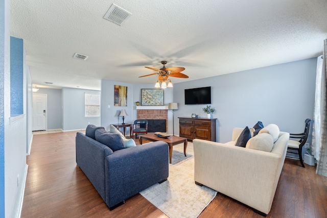 living room with ceiling fan, wood finished floors, a textured ceiling, a fireplace, and baseboards