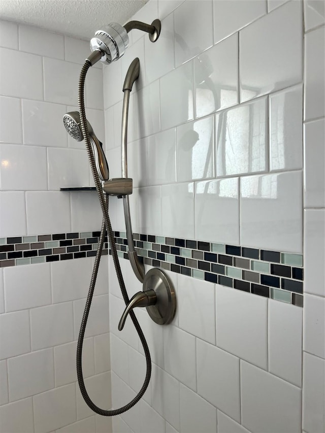 interior details with a tile shower and a textured ceiling