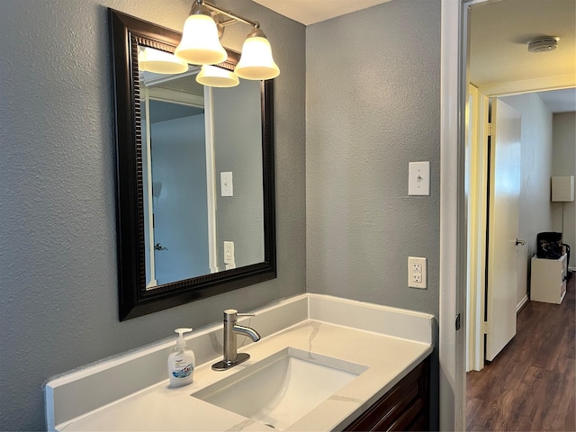 bathroom with vanity, a textured wall, and wood finished floors