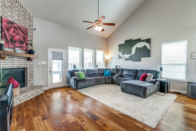 905 Bird Creek Dr, Little Elm, TX 75068 - living area with high vaulted ceiling, a ceiling fan, wood finished floors, a brick fireplace, and plenty of natural light