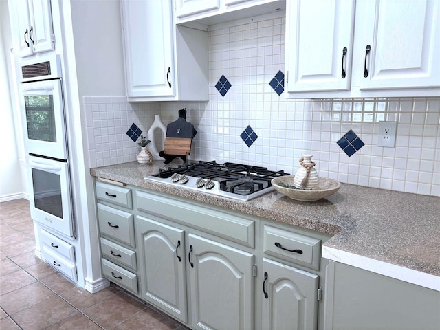 2212 Remmington Dr, Flower Mound, TX 75028 - kitchen with stainless steel gas stovetop, multiple ovens, tile patterned floors, tasteful backsplash, and light countertops