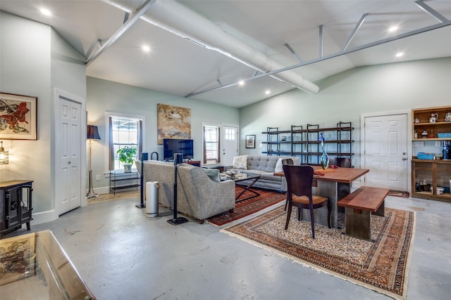 living room with concrete flooring, high vaulted ceiling, baseboards, and a wood stove