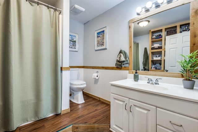full bath featuring toilet, vanity, a wainscoted wall, and wood finished floors