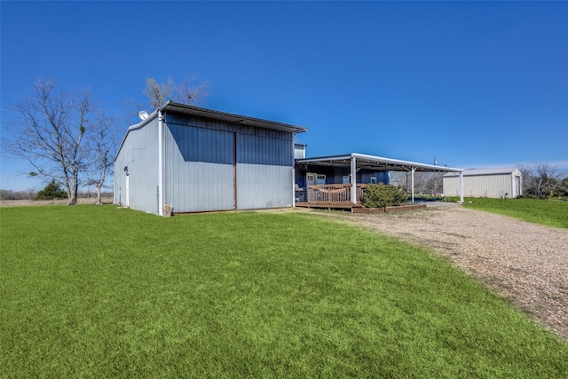 back of property featuring an outdoor structure, an outbuilding, driveway, and a lawn