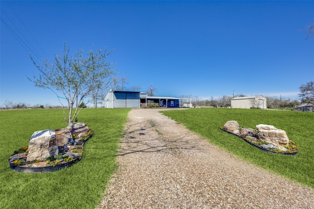 view of front of home featuring a front yard, an outbuilding, and driveway