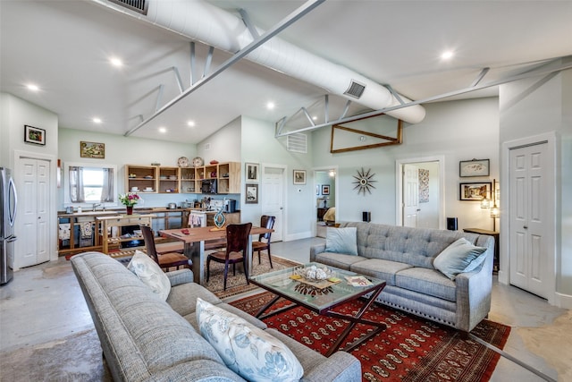 living room featuring concrete flooring, high vaulted ceiling, recessed lighting, and visible vents