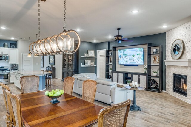 living room with light wood-type flooring, a ceiling fan, recessed lighting, and a fireplace
