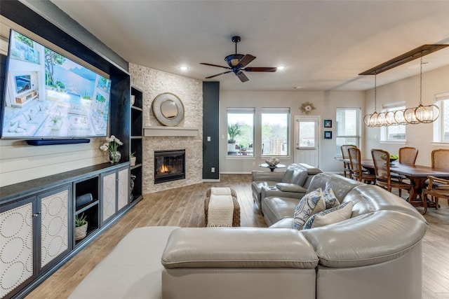 living room featuring recessed lighting, ceiling fan, a stone fireplace, and wood finished floors