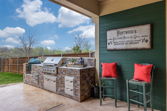 view of patio featuring fence, grilling area, and an outdoor kitchen
