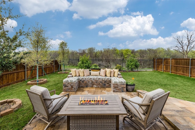 patio terrace at dusk featuring a lawn, a fenced backyard, and an outdoor living space with a fire pit