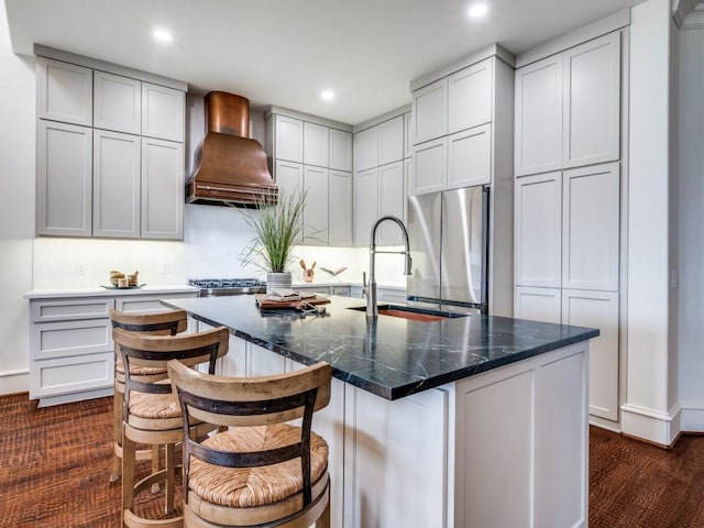 kitchen with freestanding refrigerator, recessed lighting, a sink, and premium range hood