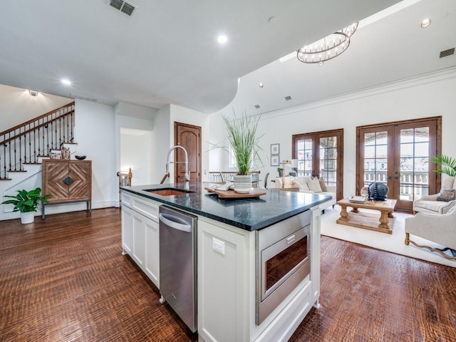 kitchen with appliances with stainless steel finishes, white cabinets, a sink, visible vents, and open floor plan