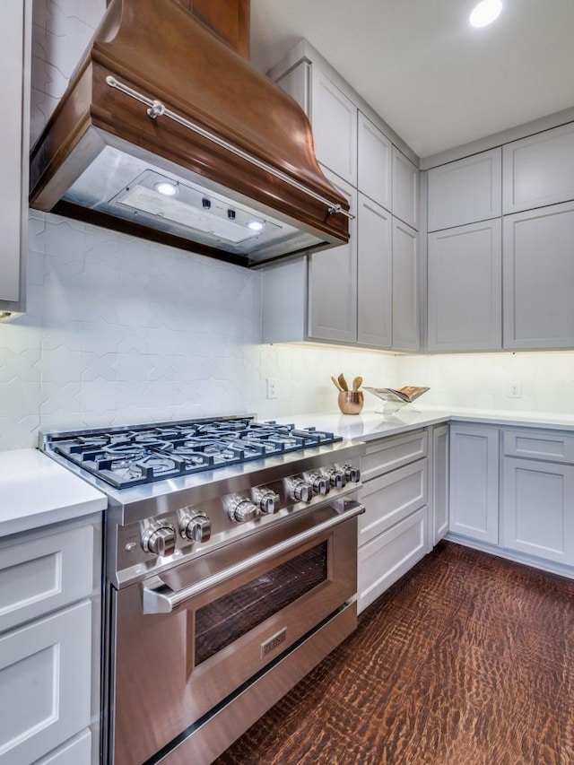 kitchen with recessed lighting, custom range hood, high end stainless steel range, light countertops, and backsplash