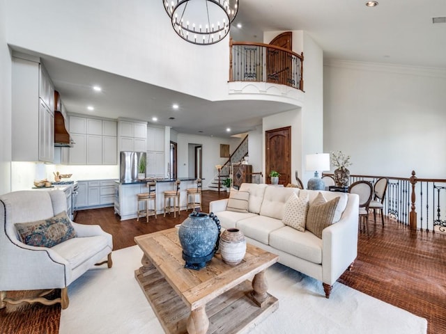 living room featuring a towering ceiling, recessed lighting, dark wood-type flooring, a notable chandelier, and stairs