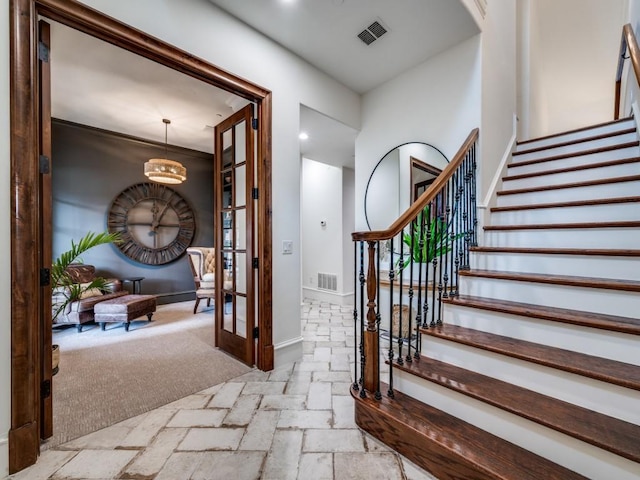 foyer entrance with baseboards, visible vents, stairway, and stone tile floors