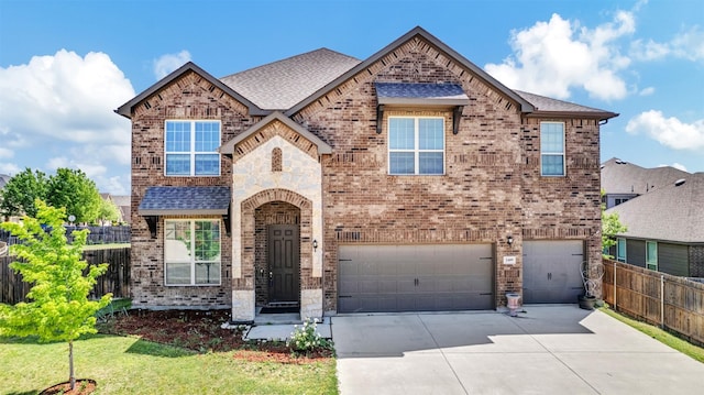 view of front of property with driveway, fence, a garage, brick siding, and roof with shingles