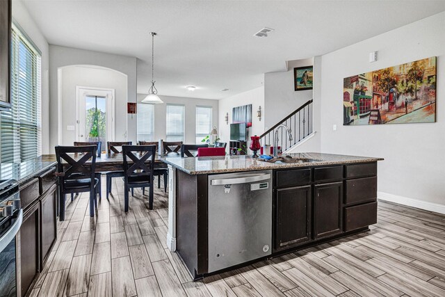 kitchen featuring dishwasher, wood finish floors, arched walkways, and a sink