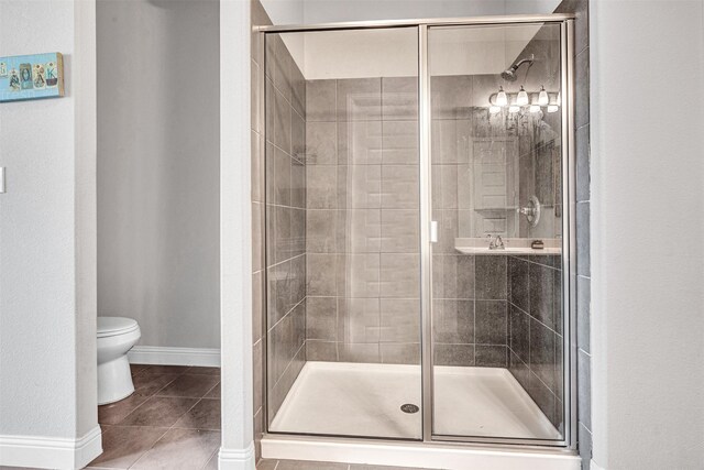 bathroom with a shower stall, toilet, and tile patterned flooring