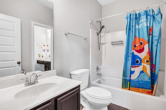 full bath with vanity, toilet, a textured wall, and shower / tub combo with curtain