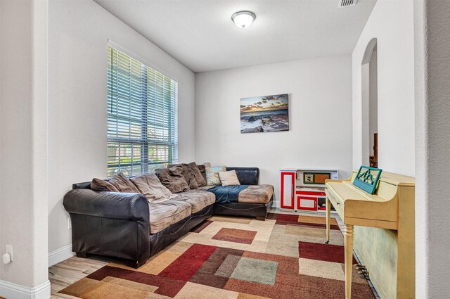 living area with baseboards, visible vents, and arched walkways