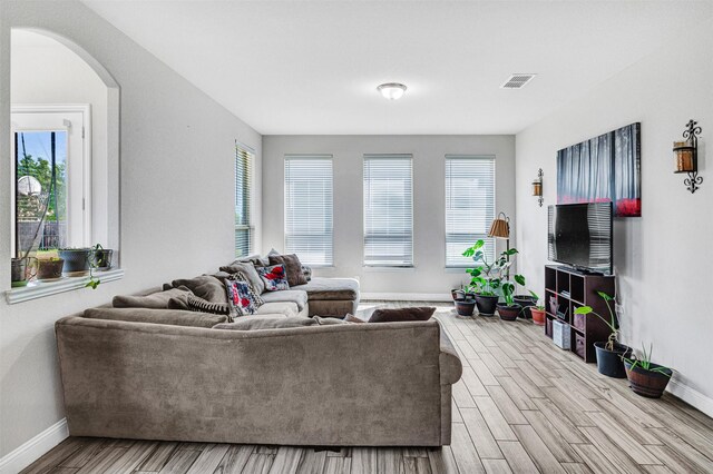 living room featuring baseboards, visible vents, wood finished floors, and a healthy amount of sunlight