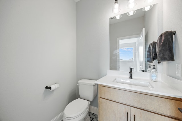 bathroom with toilet, vanity, and baseboards