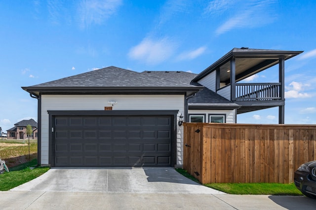 view of front of house with a balcony, fence, a garage, roof with shingles, and driveway