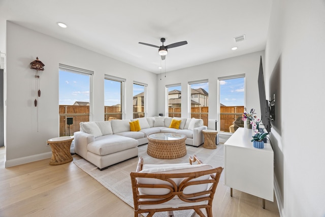 living room featuring a ceiling fan, plenty of natural light, and light wood finished floors