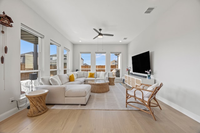 living area featuring a ceiling fan, visible vents, baseboards, and wood finished floors