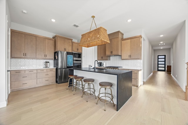 kitchen with visible vents, a kitchen bar, appliances with stainless steel finishes, a sink, and light wood-style floors