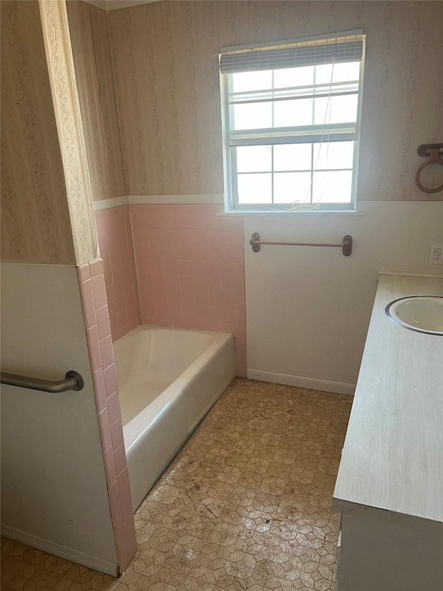 bathroom with wallpapered walls, tile patterned floors, vanity, and a bathing tub