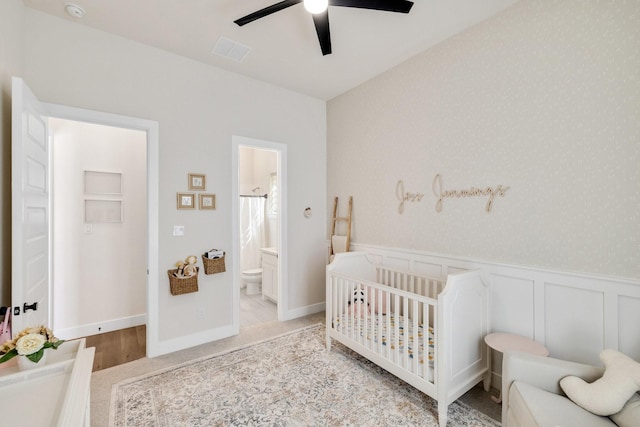 1030 Lone Grove Ln, Prosper, TX 75078 - bedroom with visible vents, ensuite bathroom, ceiling fan, a nursery area, and a wainscoted wall