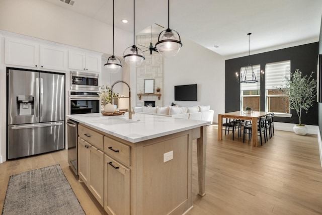 1030 Lone Grove Ln, Prosper, TX 75078 - kitchen with a notable chandelier, a sink, an island with sink, light wood-style flooring, and stainless steel appliances