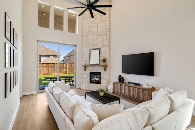 1030 Lone Grove Ln, Prosper, TX 75078 - living area with a ceiling fan, a stone fireplace, baseboards, a high ceiling, and light wood-style flooring