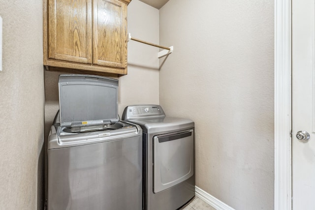laundry area featuring independent washer and dryer, light tile patterned floors, baseboards, and cabinet space
